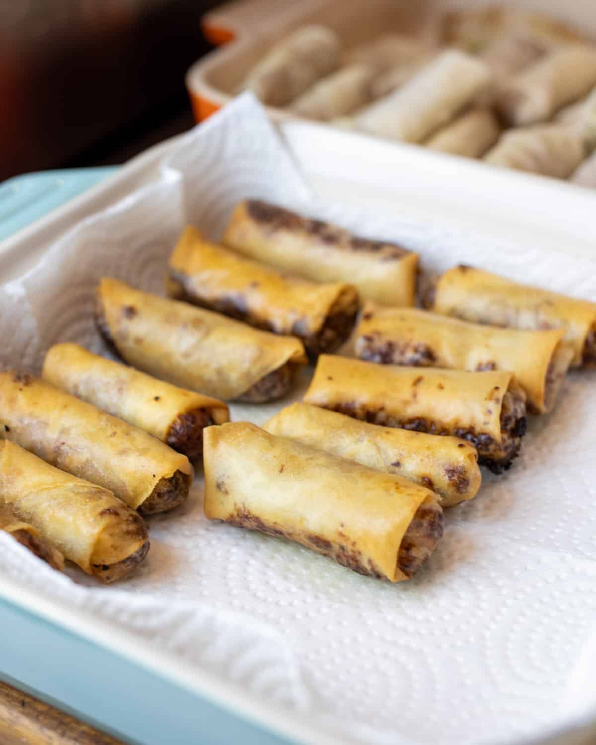 Deep fried spring rolls being drained on a paper towel.