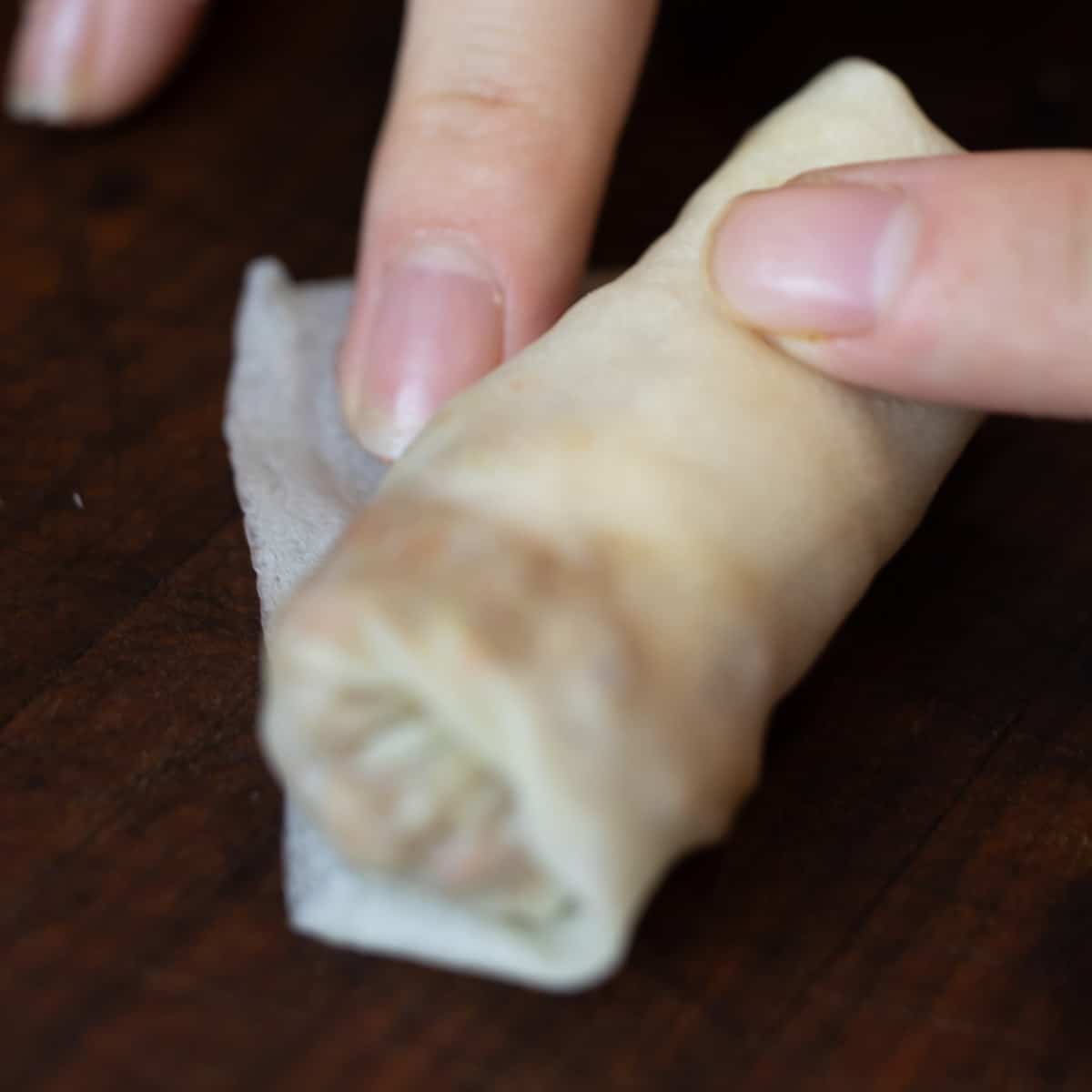 Rubbing some corn starch water on the corner of a spring roll wrapper.