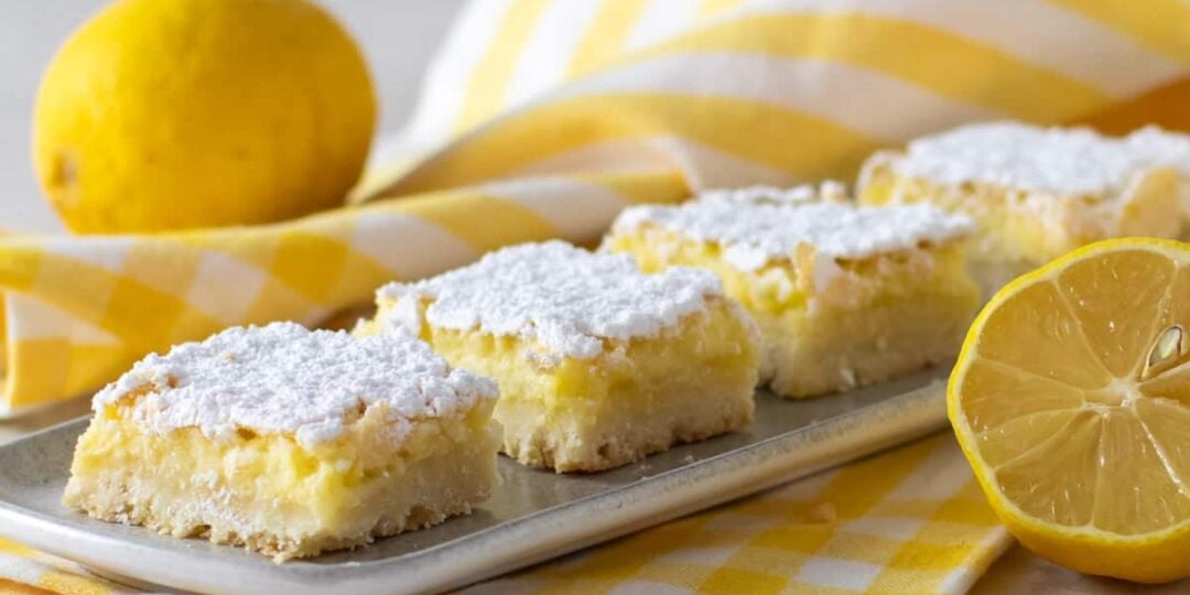 Dessert squares on a plate surrounded by a couple lemons.