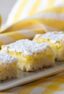 Dessert squares on a plate surrounded by a couple lemons.