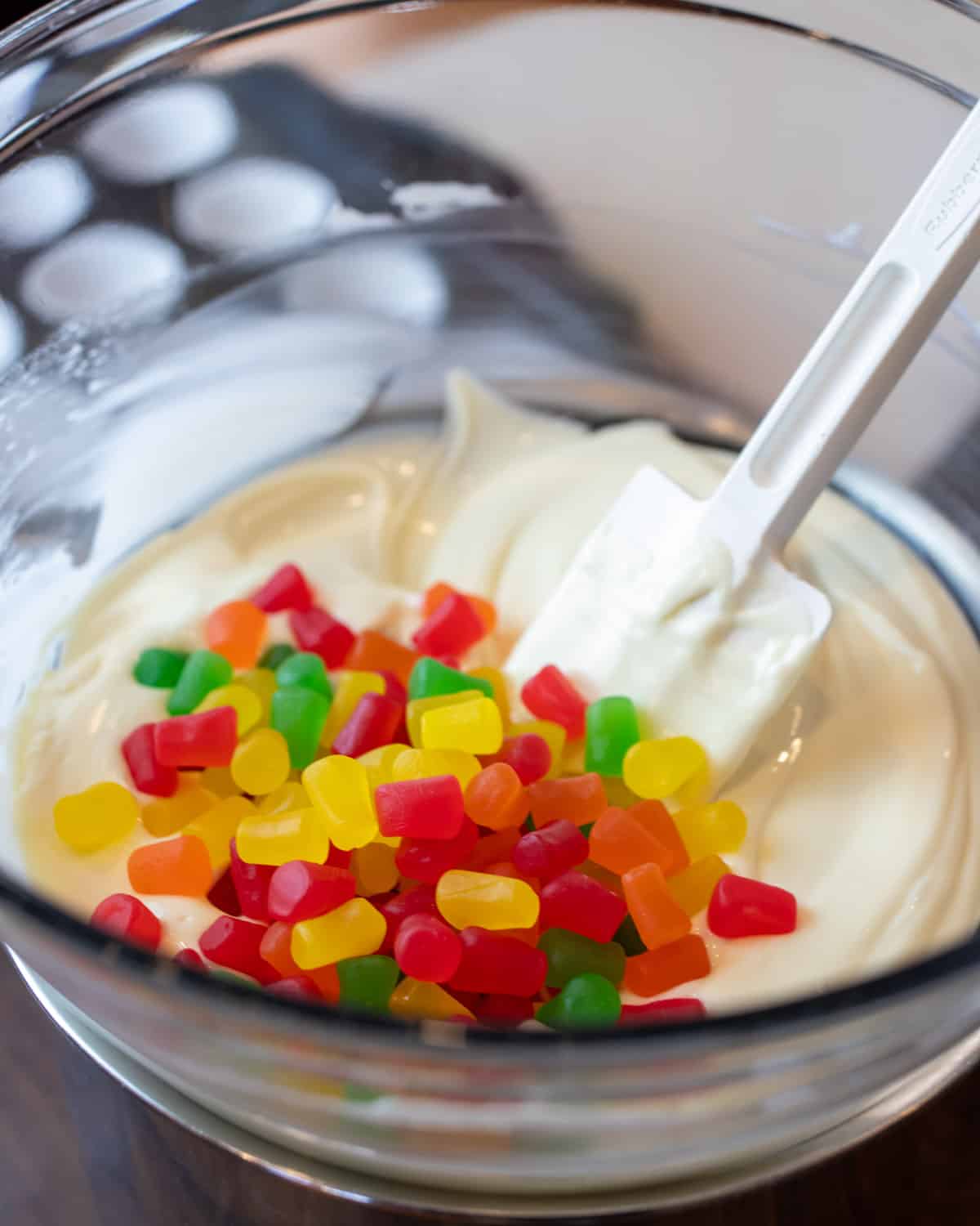 Candy gumdrops added to a bowl with chocolate.