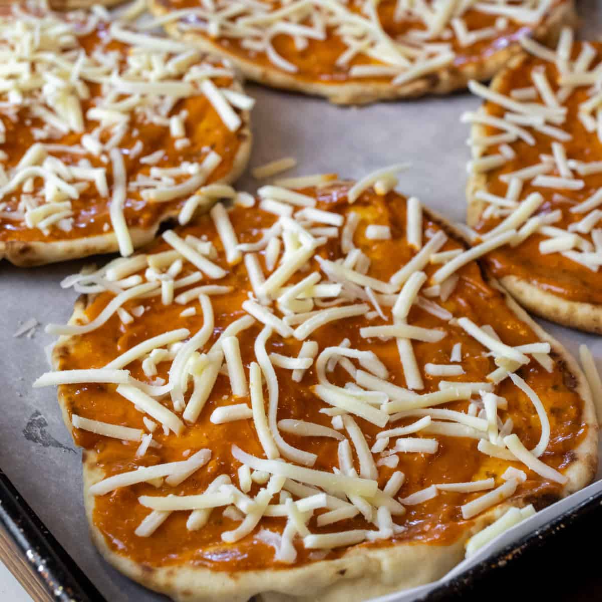 Grated cheese sprinkled on some naan bread.
