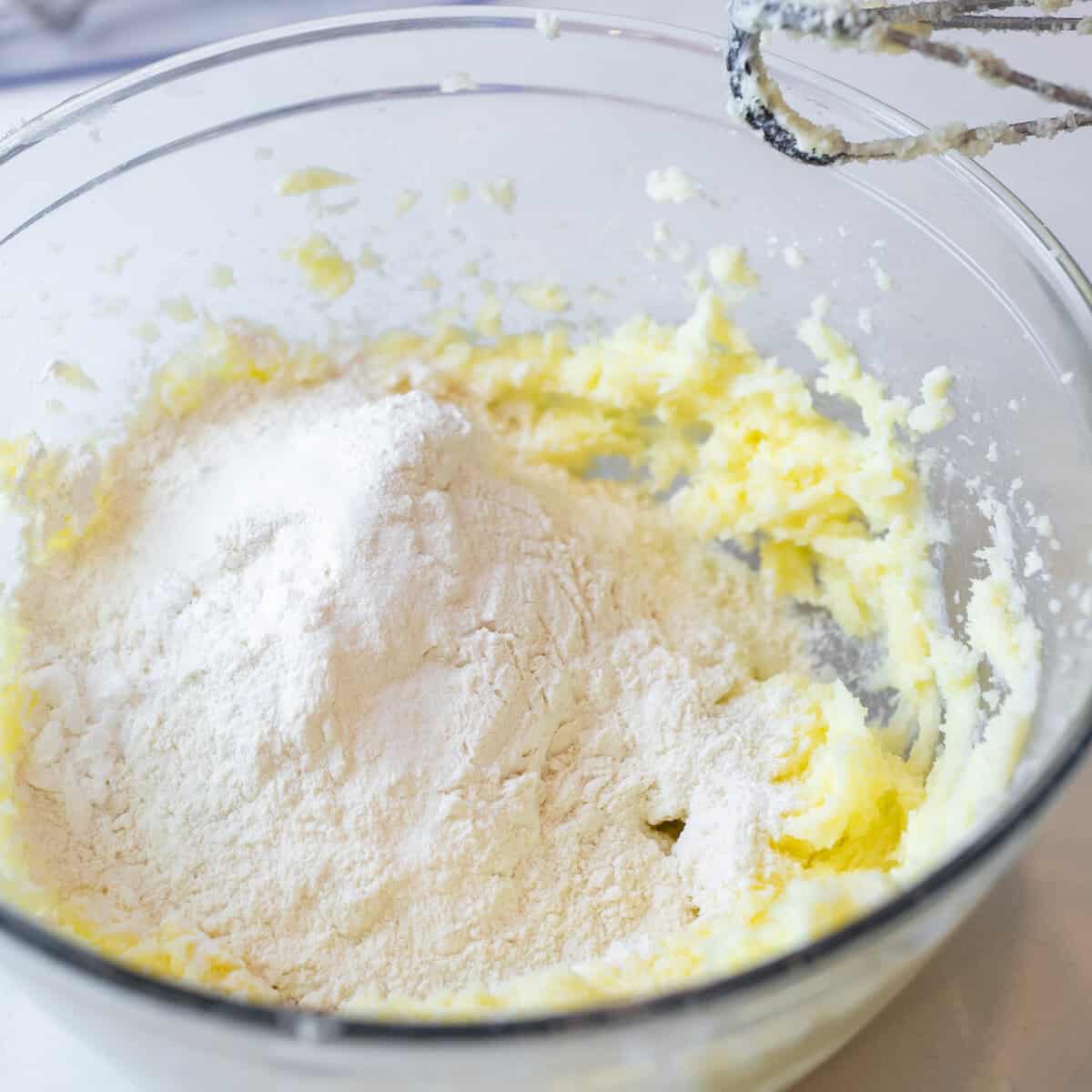 Flour added to the bowl with the butter and sugar mixture.