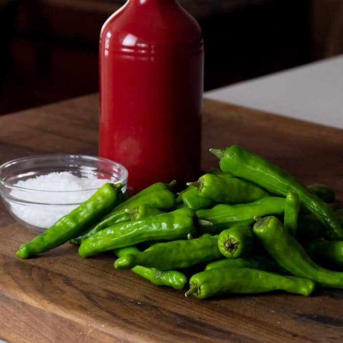 shishito peppers on a cutting board with salt